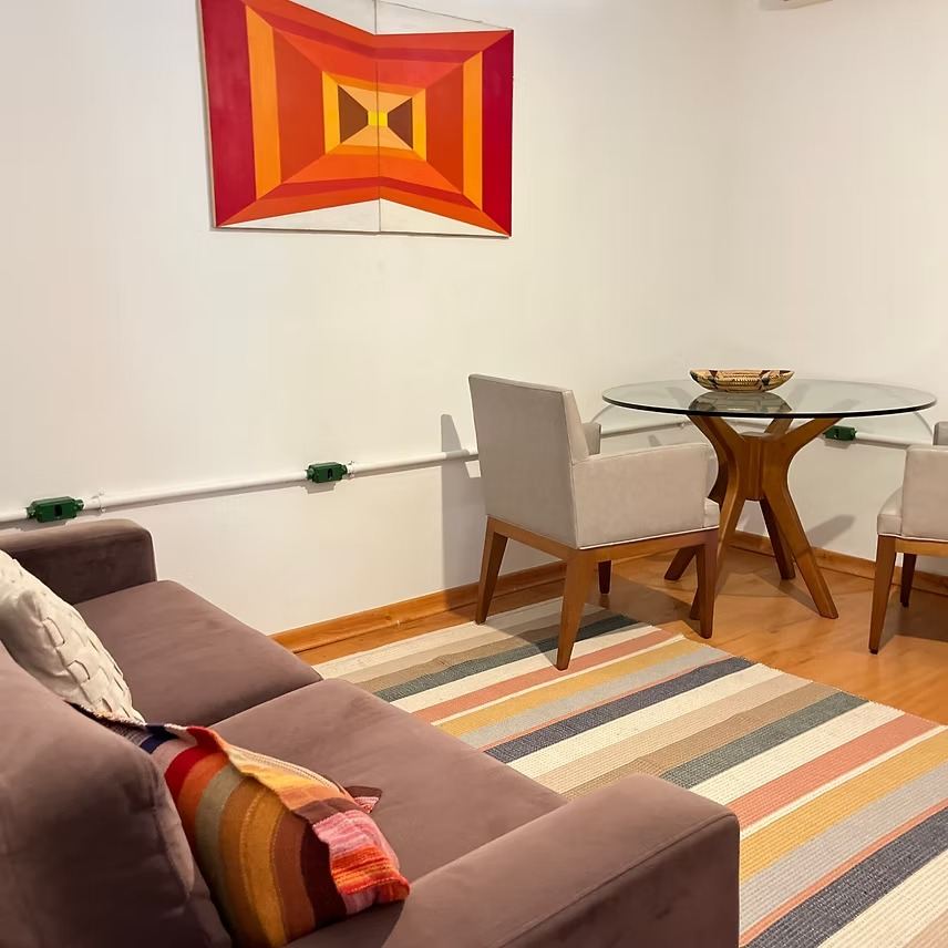 Sala de atendimento com sofá, mesa de reunião e quadro